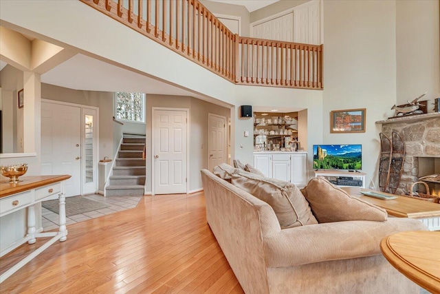 2181 Oak Hill Dr, Buck Hill Falls, PA 18323 - living room featuring a fireplace, light wood-style flooring, a towering ceiling, stairway, and indoor bar