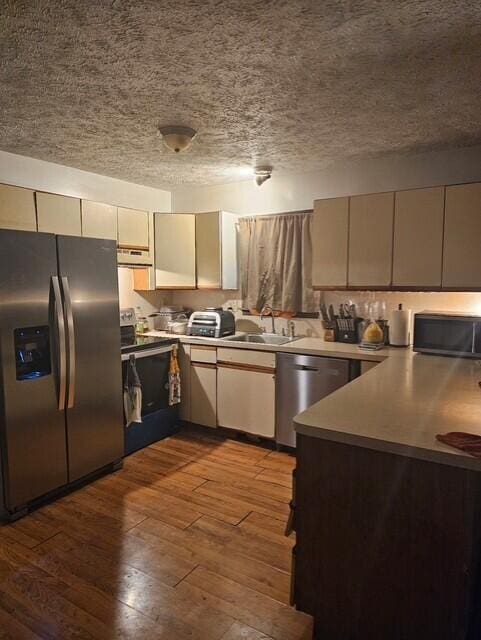 8192 Elk Ct, Tobyhanna, PA 18466 - kitchen with dark wood-style floors, range hood, a textured ceiling, a sink, and appliances with stainless steel finishes