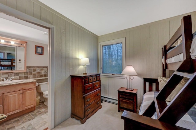 bedroom featuring baseboard heating, ensuite bath, and a sink