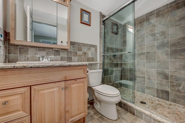 bathroom featuring tasteful backsplash, a shower stall, toilet, and vanity