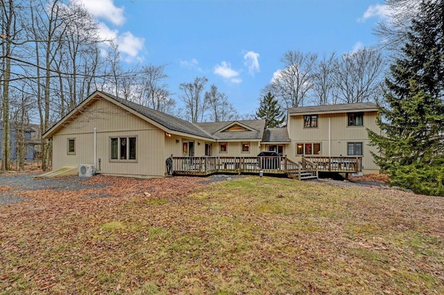 rear view of property with ac unit, a wooden deck, and a lawn