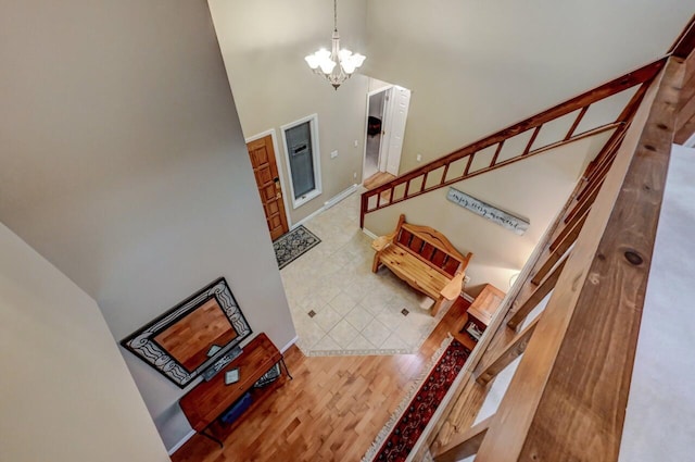 foyer entrance with wood finished floors, a high ceiling, an inviting chandelier, baseboards, and stairs