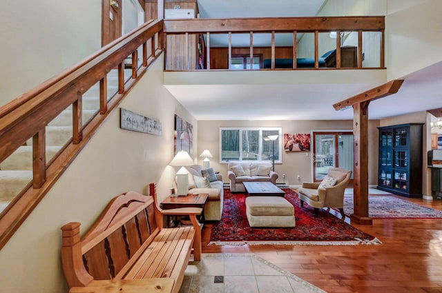 living area featuring stairway, baseboards, wood finished floors, and a towering ceiling