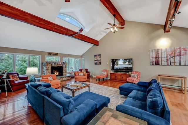 living room with ceiling fan, beam ceiling, a stone fireplace, wood finished floors, and high vaulted ceiling