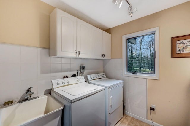 laundry area with washer and clothes dryer, cabinet space, tile walls, and a sink