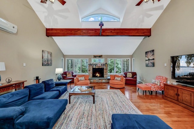 living room featuring beamed ceiling, a stone fireplace, and a ceiling fan