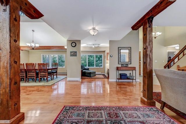 foyer featuring an inviting chandelier, wood finished floors, baseboards, and vaulted ceiling