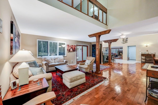 living area featuring a high ceiling, baseboards, and wood-type flooring