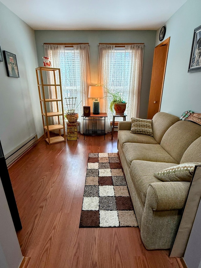 living area featuring a baseboard heating unit, wood finished floors, and a healthy amount of sunlight
