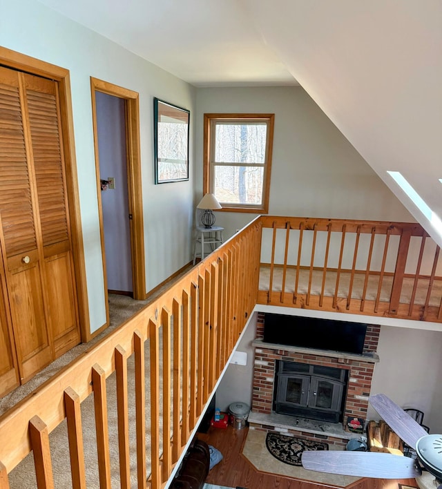 stairway with a fireplace, wood finished floors, and lofted ceiling