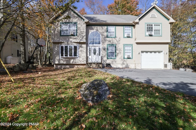 view of front of property with driveway, an attached garage, a front lawn, and entry steps