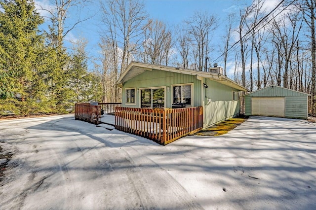 view of front facade featuring a deck, a garage, an outdoor structure, driveway, and a chimney