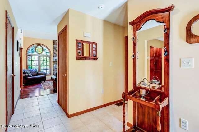 hall featuring light tile patterned floors and baseboards