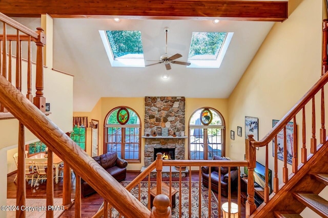 living area with high vaulted ceiling, a skylight, a healthy amount of sunlight, and stairs