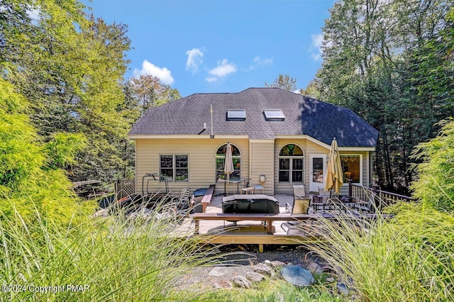 back of house with a shingled roof and a deck