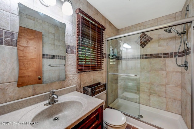 full bathroom with toilet, vanity, a shower stall, and tile walls