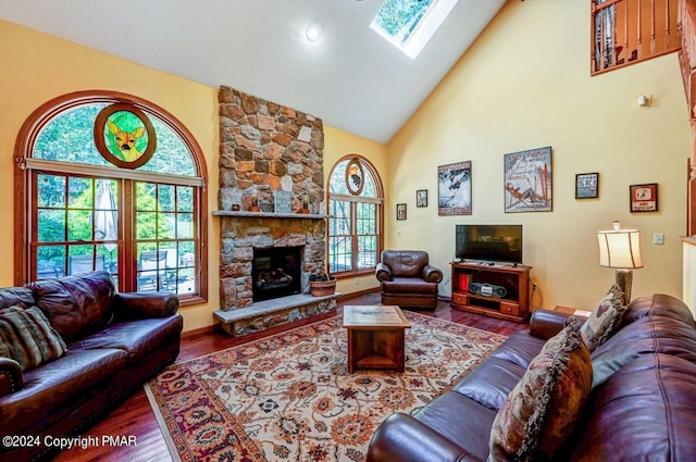 living area featuring high vaulted ceiling, a fireplace, a skylight, and wood finished floors