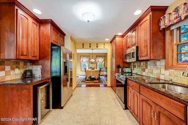 kitchen featuring appliances with stainless steel finishes, wine cooler, dark stone counters, and a sink