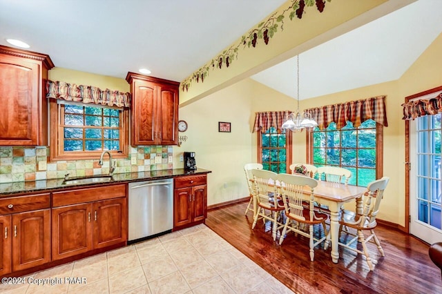 kitchen featuring decorative backsplash, dishwasher, dark stone countertops, a chandelier, and a sink