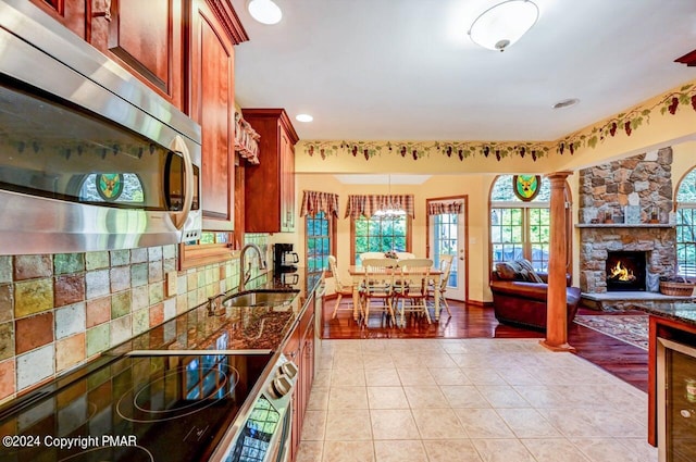 kitchen featuring a fireplace, a sink, electric stove, decorative backsplash, and stainless steel microwave