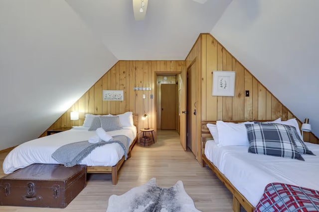 bedroom with wooden walls, lofted ceiling, and light wood-type flooring