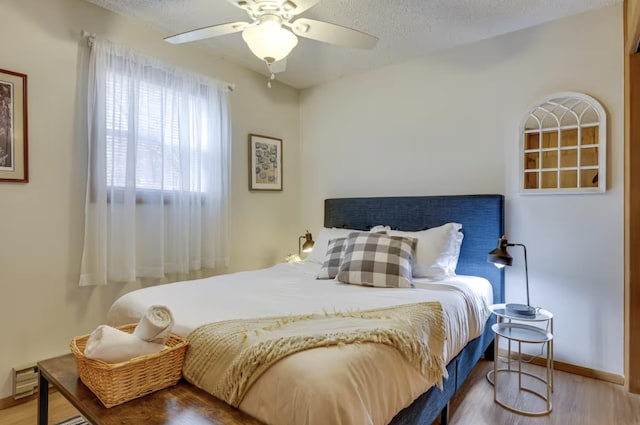 bedroom featuring baseboards, a textured ceiling, ceiling fan, and wood finished floors
