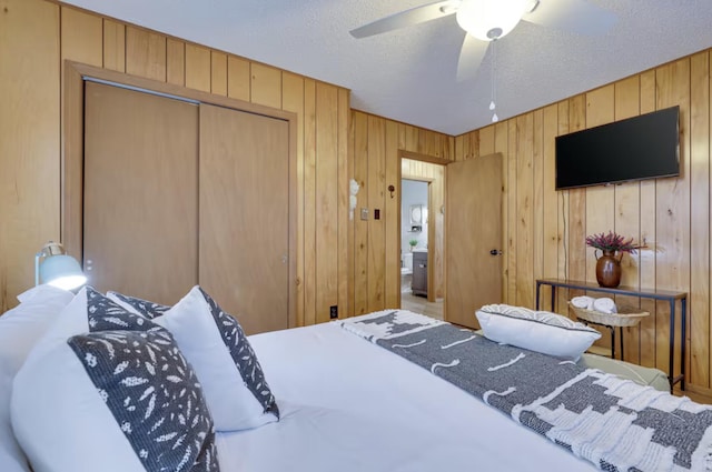 bedroom featuring a closet, wood walls, a textured ceiling, and a ceiling fan