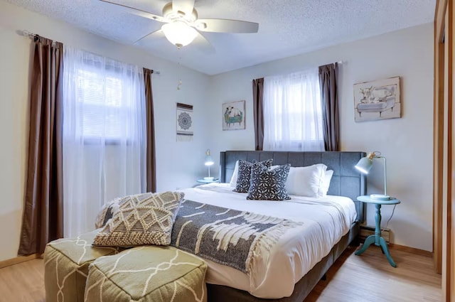 bedroom with a textured ceiling, multiple windows, and wood finished floors