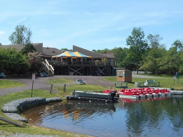 surrounding community with a deck with water view, a yard, a dock, and stairway
