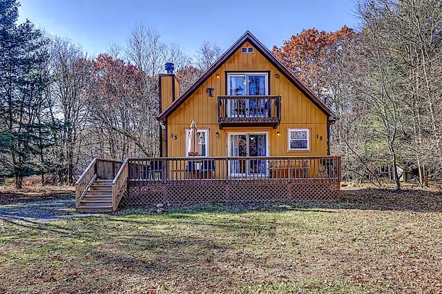 back of house with a wooden deck, a chimney, a yard, and a balcony