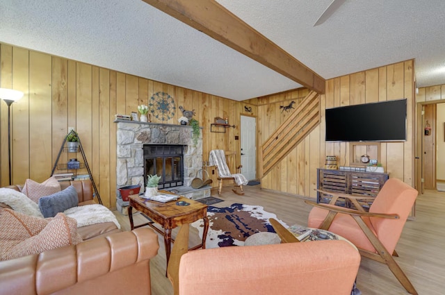living area featuring beam ceiling, wood walls, a textured ceiling, and wood finished floors