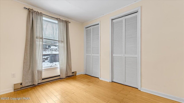 115 Aspen Cir E, Stroudsburg, PA 18302 - unfurnished bedroom with multiple closets, crown molding, light wood-type flooring, and baseboard heating