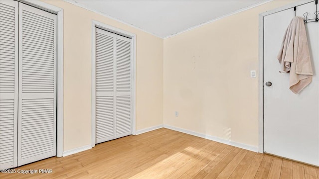 115 Aspen Cir E, Stroudsburg, PA 18302 - unfurnished bedroom with light wood-style flooring, ornamental molding, and two closets