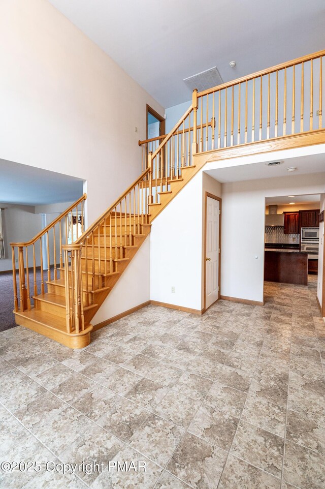 stairway with baseboards and a towering ceiling