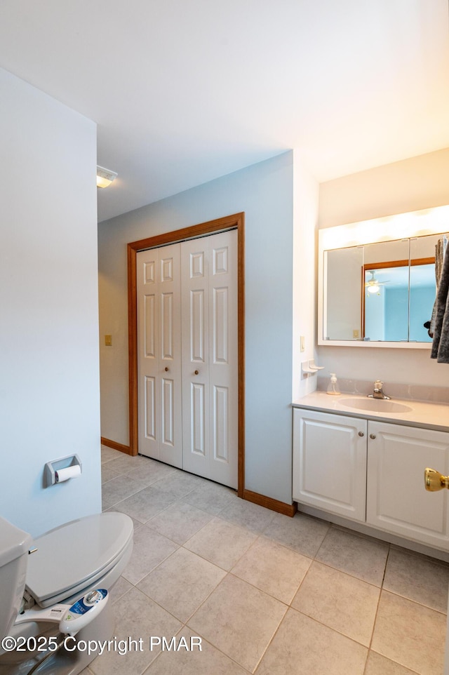 bathroom with tile patterned flooring, toilet, vanity, and baseboards