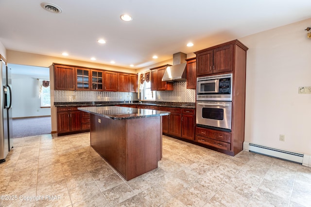 kitchen with tasteful backsplash, visible vents, wall chimney range hood, appliances with stainless steel finishes, and a baseboard radiator