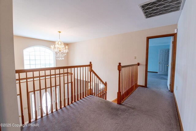 corridor with visible vents, baseboards, carpet, an upstairs landing, and a notable chandelier