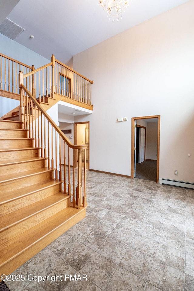 staircase with visible vents, baseboards, baseboard heating, a high ceiling, and a notable chandelier