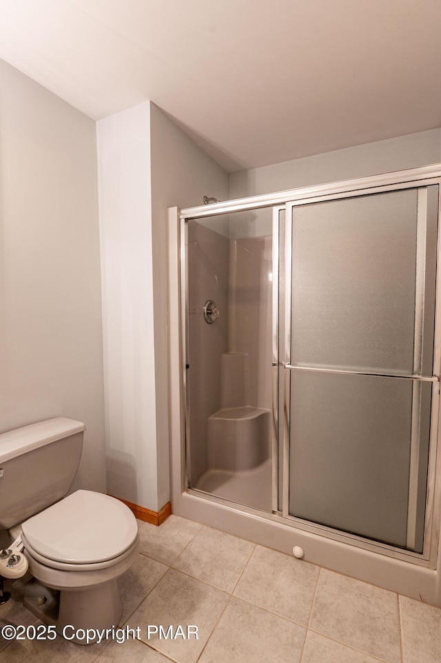 bathroom featuring baseboards, toilet, a stall shower, and tile patterned flooring