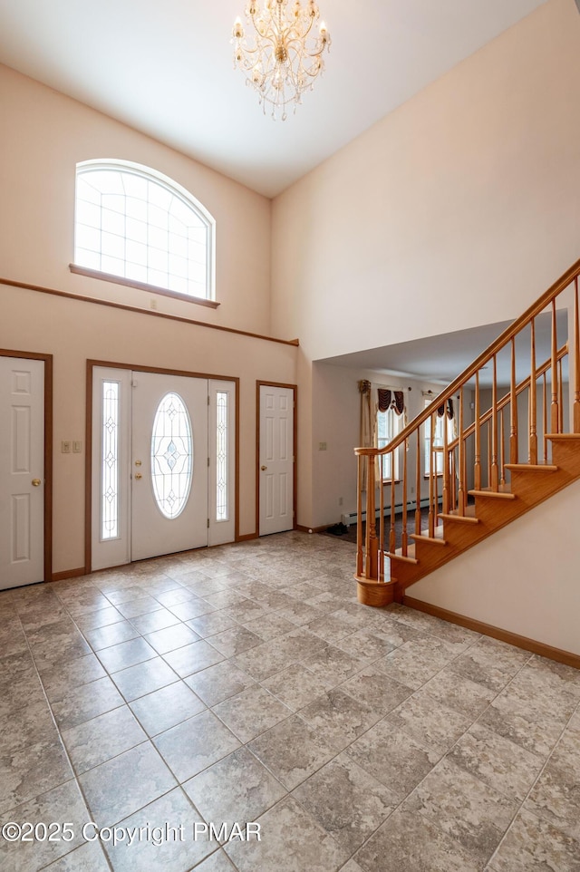 foyer entrance featuring stairway, baseboards, a chandelier, and a towering ceiling