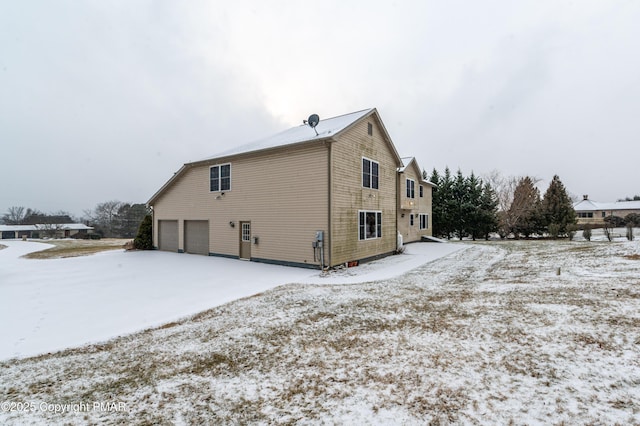 snow covered back of property featuring a garage