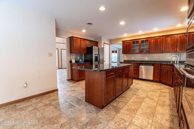 kitchen with baseboards, stainless steel appliances, decorative backsplash, glass insert cabinets, and a center island