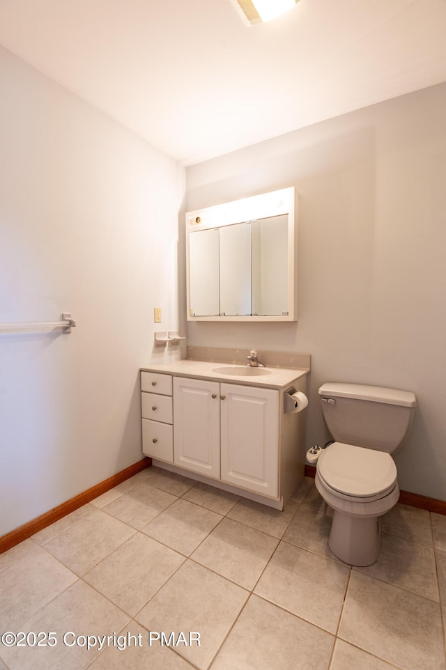 half bath with tile patterned flooring, toilet, vanity, and baseboards