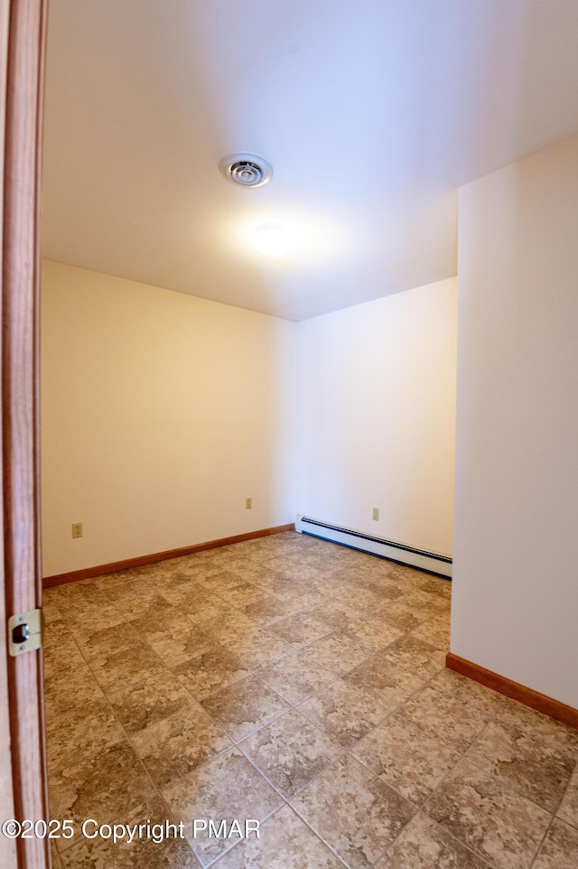 empty room with a baseboard heating unit, baseboards, and visible vents