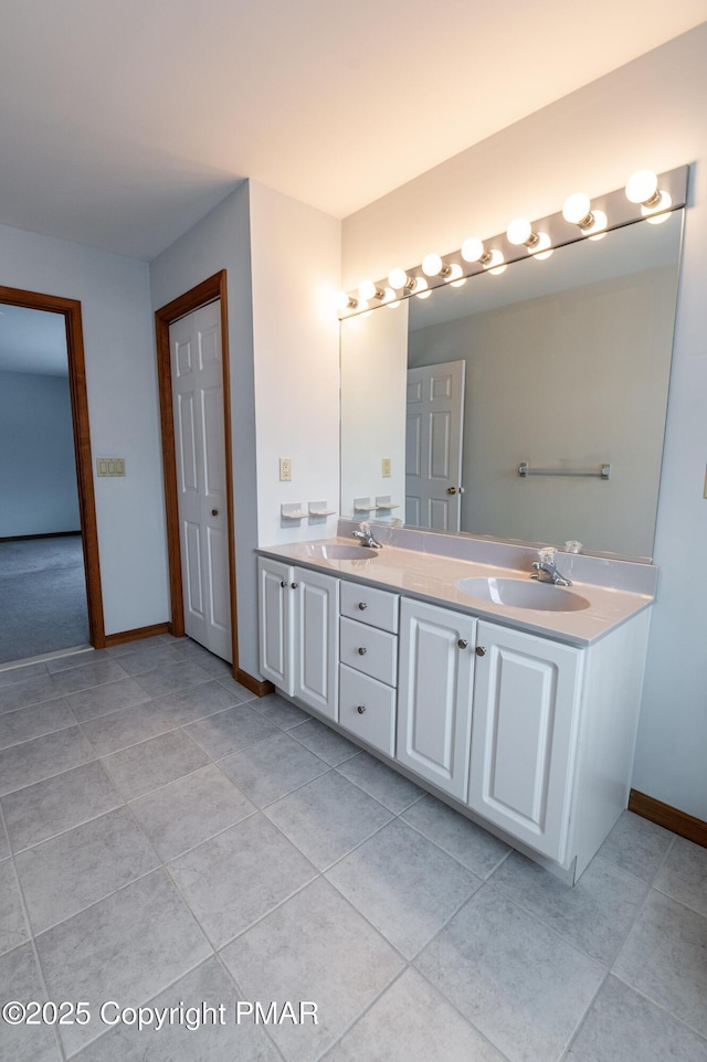 full bathroom with double vanity, tile patterned floors, baseboards, and a sink