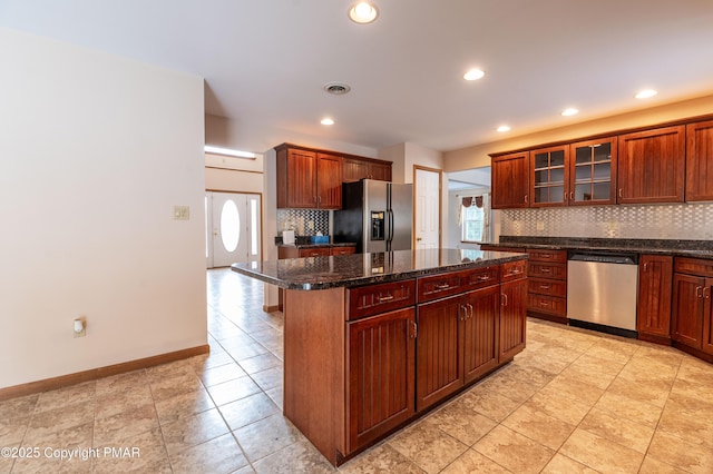 kitchen featuring tasteful backsplash, a center island, stainless steel appliances, glass insert cabinets, and baseboards