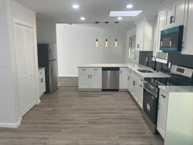 3354 Trafalgar Ave, East Stroudsburg, PA 18302 - kitchen featuring stainless steel appliances, a skylight, a peninsula, white cabinetry, and recessed lighting