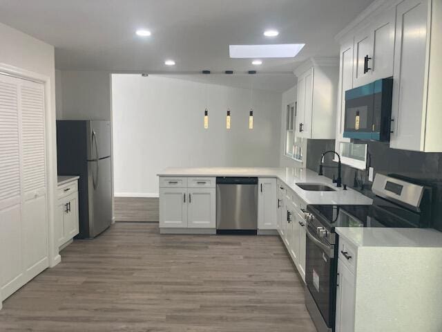 3354 Trafalgar Ave, East Stroudsburg, PA 18302 - kitchen with stainless steel appliances, a skylight, a peninsula, wood finished floors, and light countertops