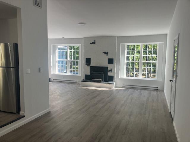 3354 Trafalgar Ave, East Stroudsburg, PA 18302 - unfurnished living room featuring a baseboard heating unit, wood finished floors, and a fireplace with raised hearth