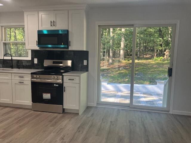 3354 Trafalgar Ave, East Stroudsburg, PA 18302 - kitchen featuring stainless steel electric stove, light wood-type flooring, decorative backsplash, white cabinetry, and light countertops